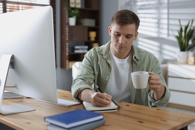 Photo of Handsome man working with computer at desk indoors. Home office