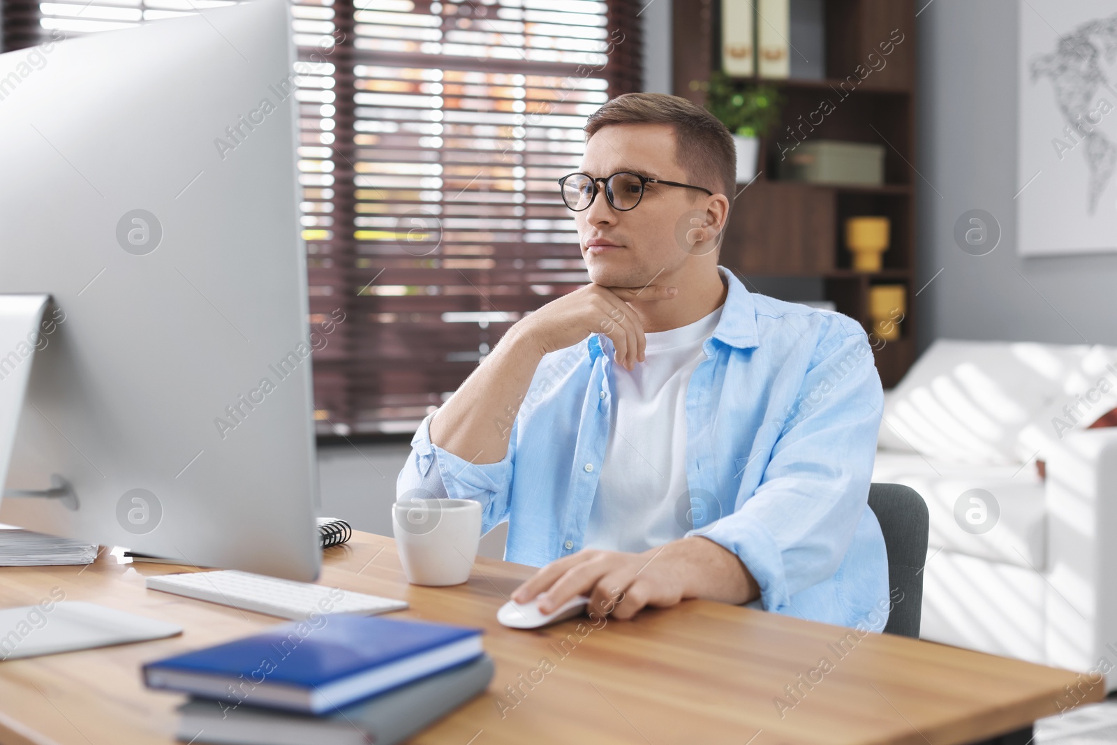 Photo of Handsome man working with computer at desk indoors. Home office