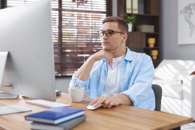 Photo of Handsome man working with computer at desk indoors. Home office