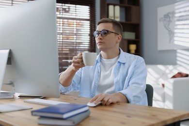 Photo of Handsome man working with computer at desk indoors. Home office