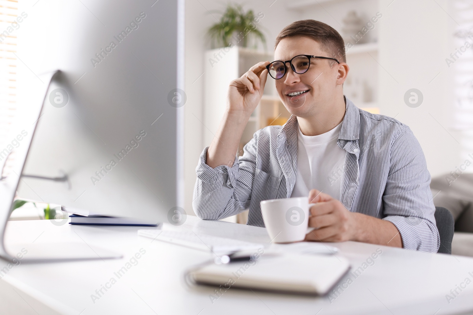 Photo of Happy man working with computer at desk indoors. Home office