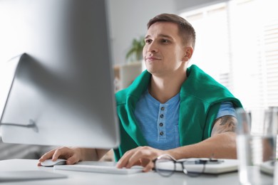 Handsome man working with computer at desk indoors. Home office