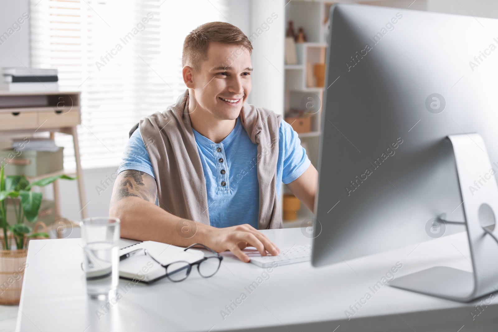 Photo of Happy man working with computer at desk indoors. Home office