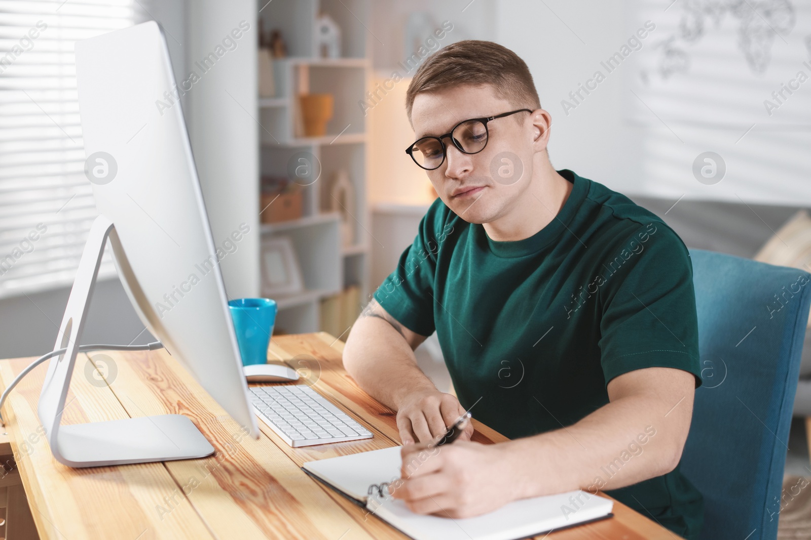 Photo of Handsome man working with computer at desk indoors. Home office