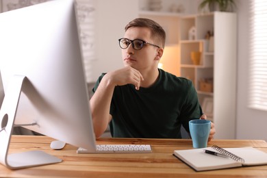 Photo of Handsome man working with computer at desk indoors. Home office