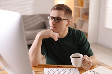 Handsome man working with computer at desk indoors. Home office