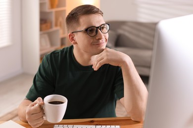 Handsome man working with computer at desk indoors. Home office