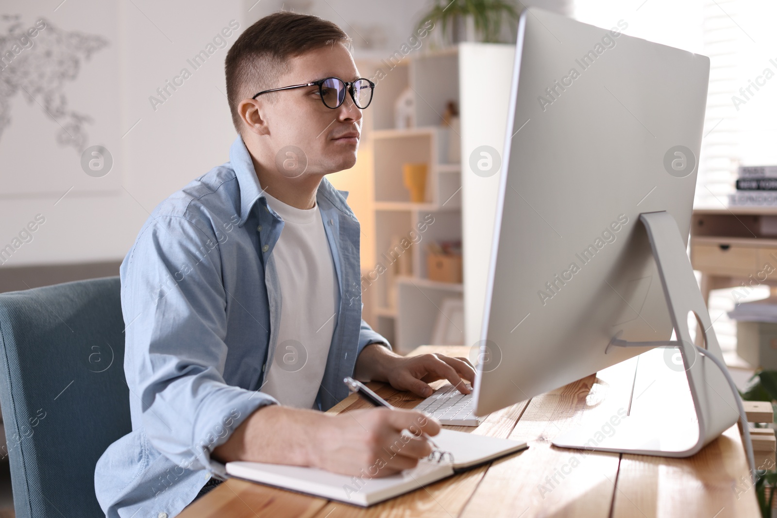 Photo of Handsome man working with computer at desk indoors. Home office