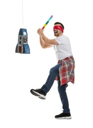 Photo of Blindfolded man hitting rocket shaped pinata with stick on white background