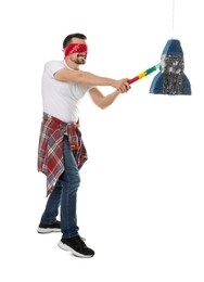 Photo of Blindfolded man hitting rocket shaped pinata with stick on white background