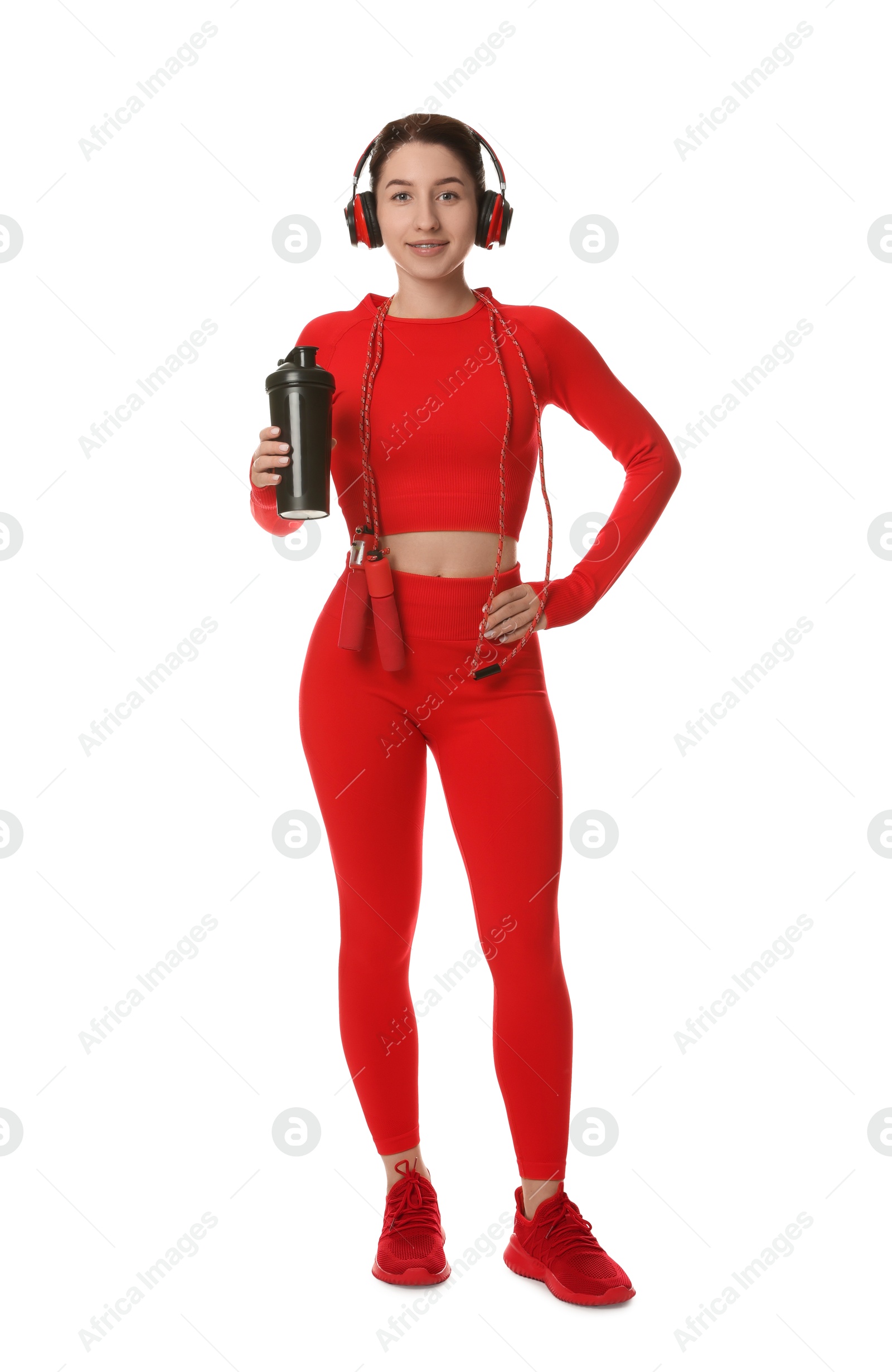 Photo of Woman in sportswear and headphones holding shaker on white background