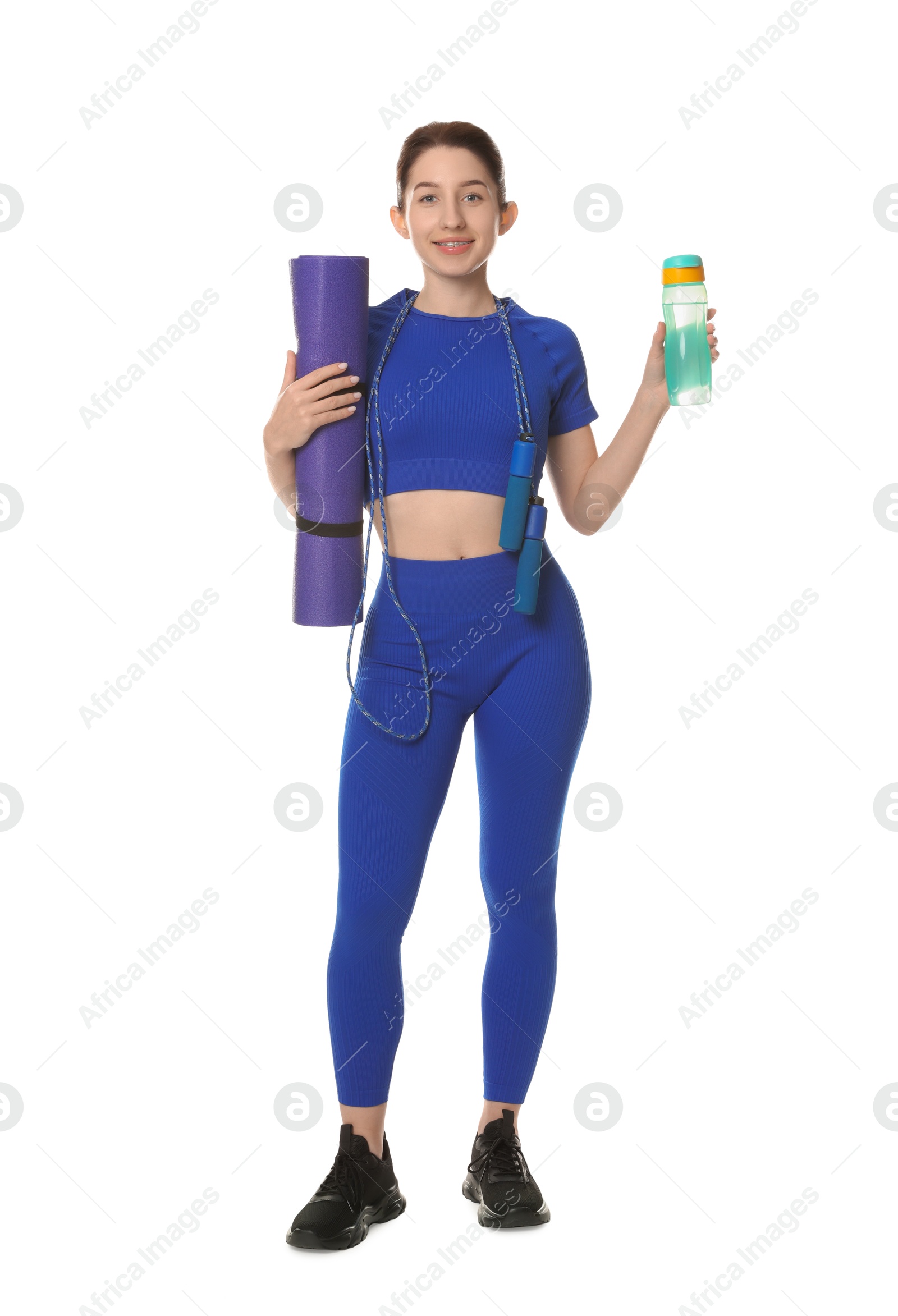 Photo of Woman in sportswear with fitness mat, bottle and skipping rope on white background