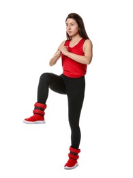 Woman in sportswear exercising with ankle weights on white background