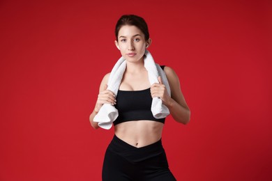 Woman in sportswear with towel on red background