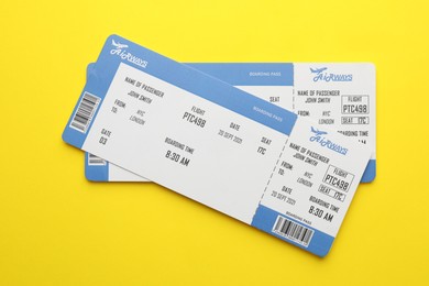 Photo of Travel agency. Flight tickets on yellow background, top view