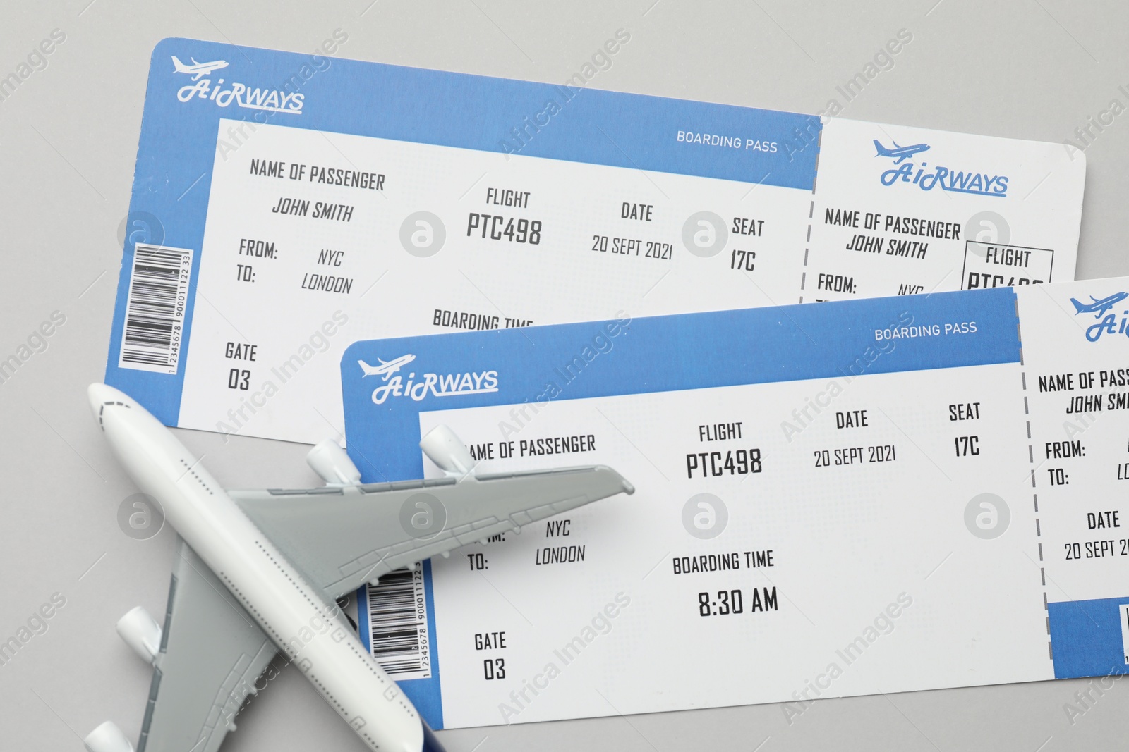 Photo of Travel agency. Flight tickets and plane model on grey background, flat lay