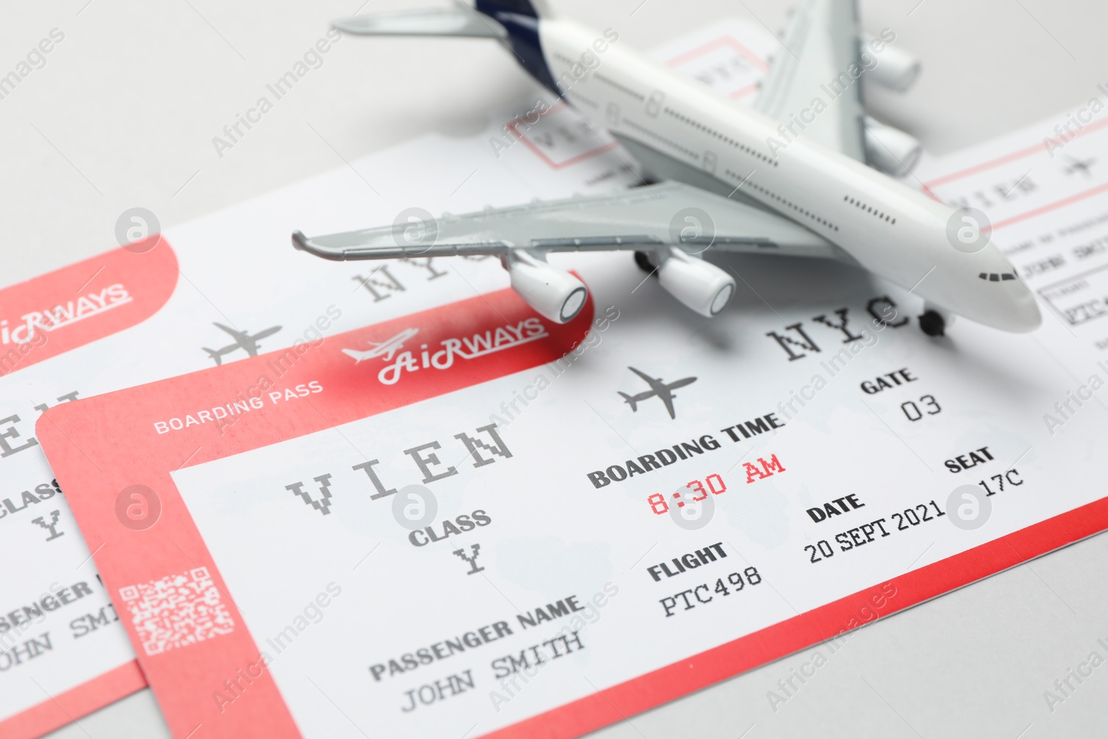 Photo of Travel agency. Flight tickets and plane model on grey background, closeup