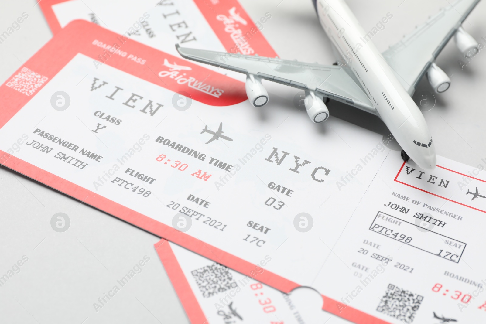 Photo of Travel agency. Flight tickets and plane model on grey background, closeup