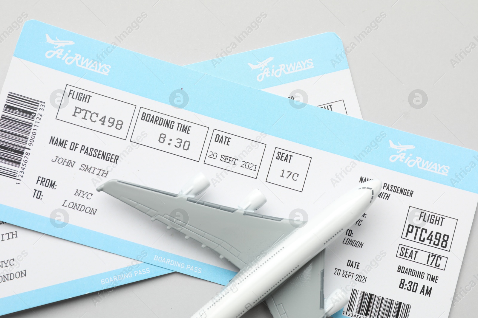 Photo of Travel agency. Flight tickets and plane model on grey background, flat lay