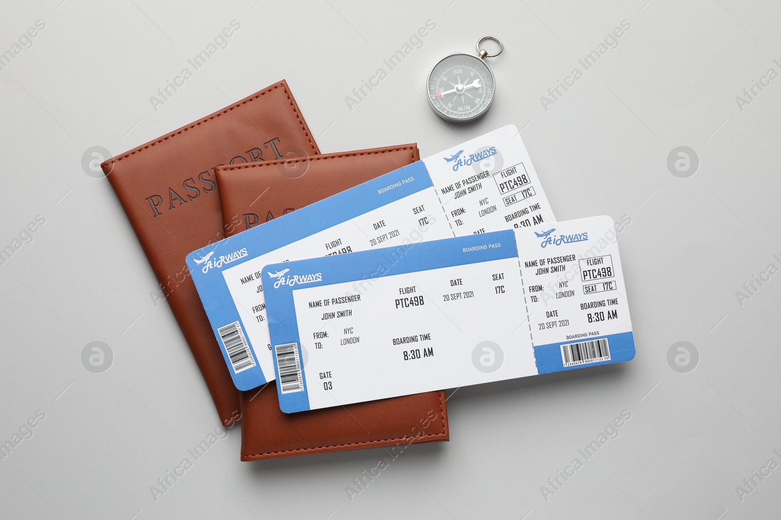 Photo of Travel agency. Flight tickets, passports and compass on grey background, flat lay