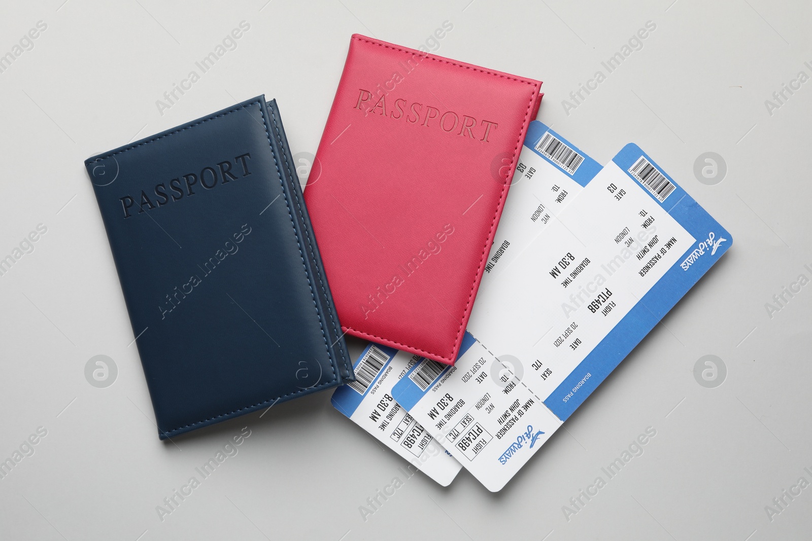 Photo of Travel agency. Flight tickets and passports on grey background, flat lay