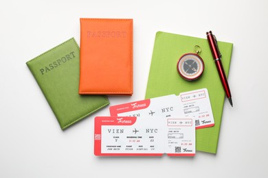 Travel agency. Flight tickets, passports, compass, notebook and pen on light background, flat lay