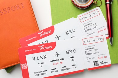 Photo of Travel agency. Flight tickets, passports, notebook and pen on light background, flat lay