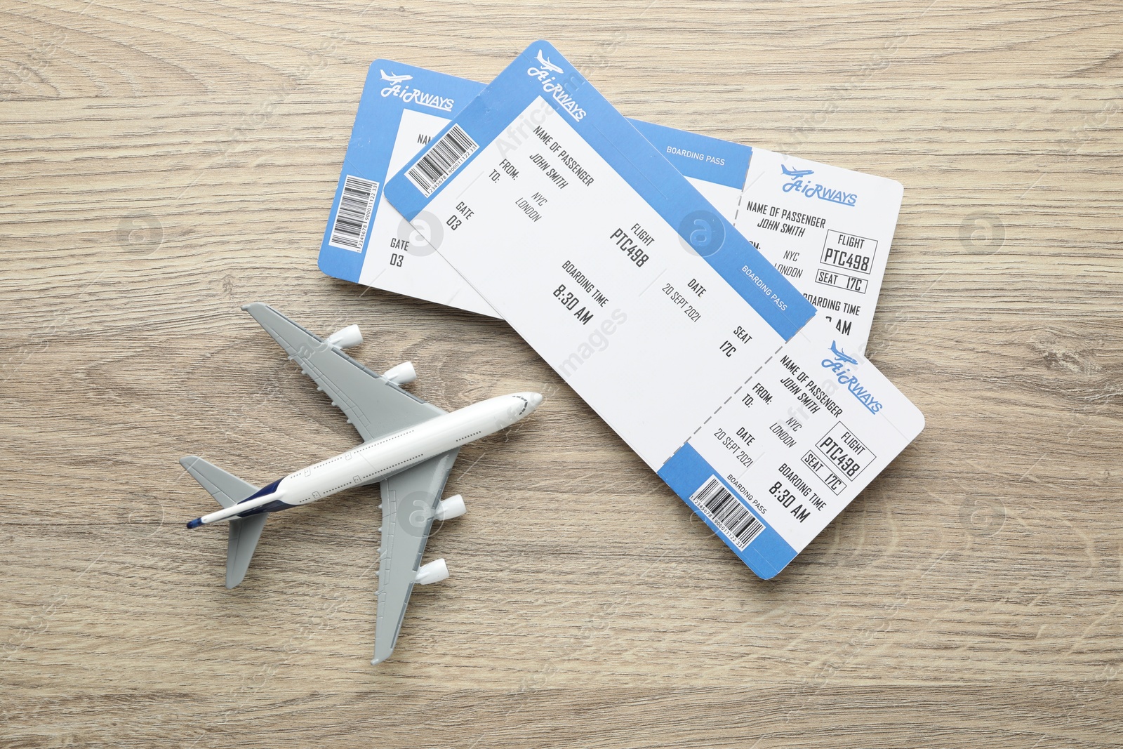 Photo of Travel agency. Flight tickets and plane model on wooden table, flat lay