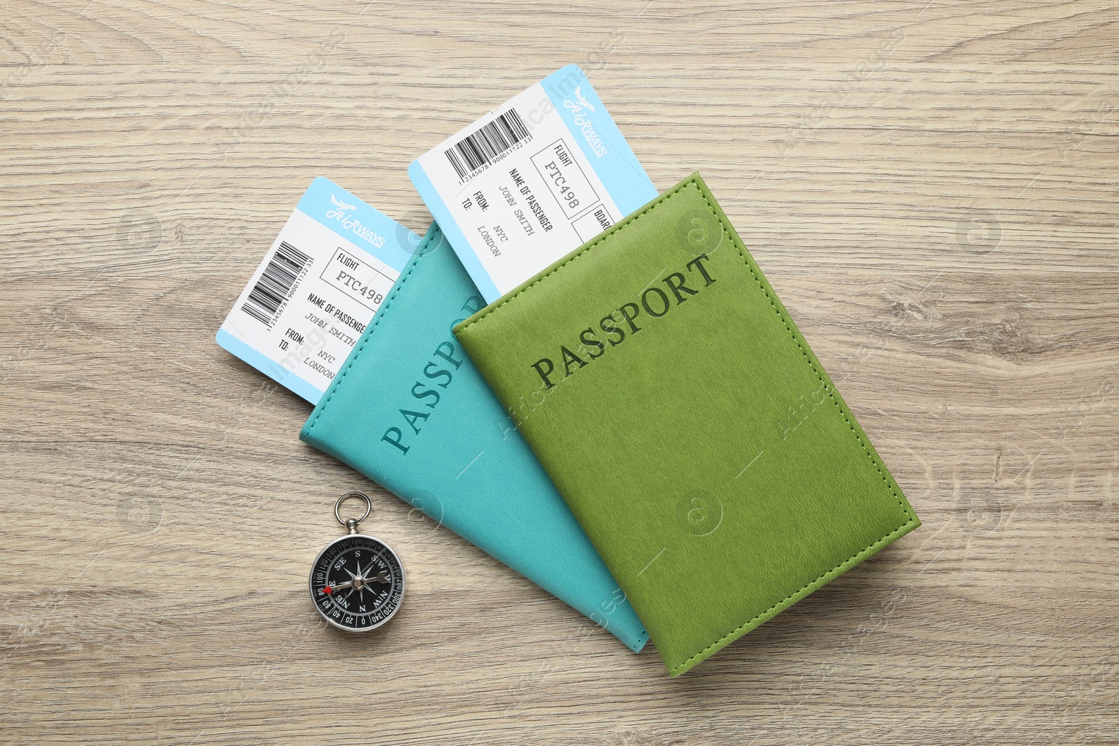 Photo of Travel agency. Flight tickets, passports and compass on wooden table, flat lay