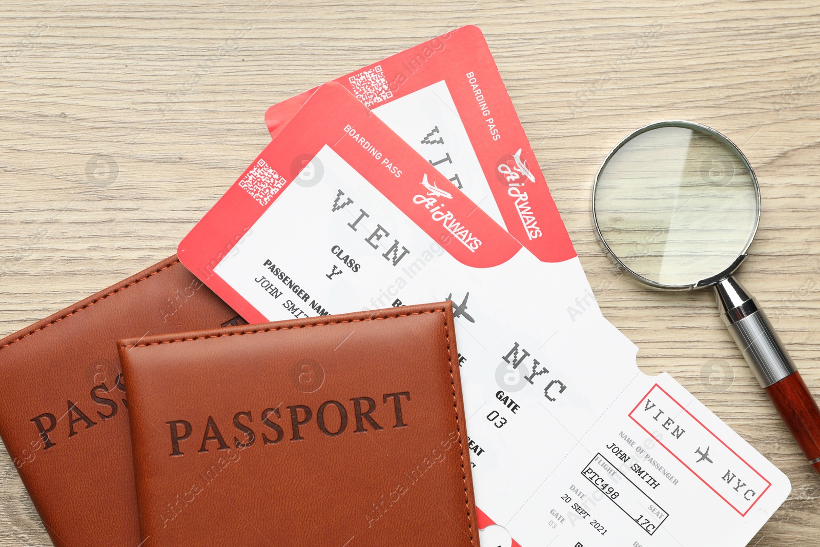 Photo of Travel agency. Flight tickets, passports and magnifying glass on wooden table, flat lay