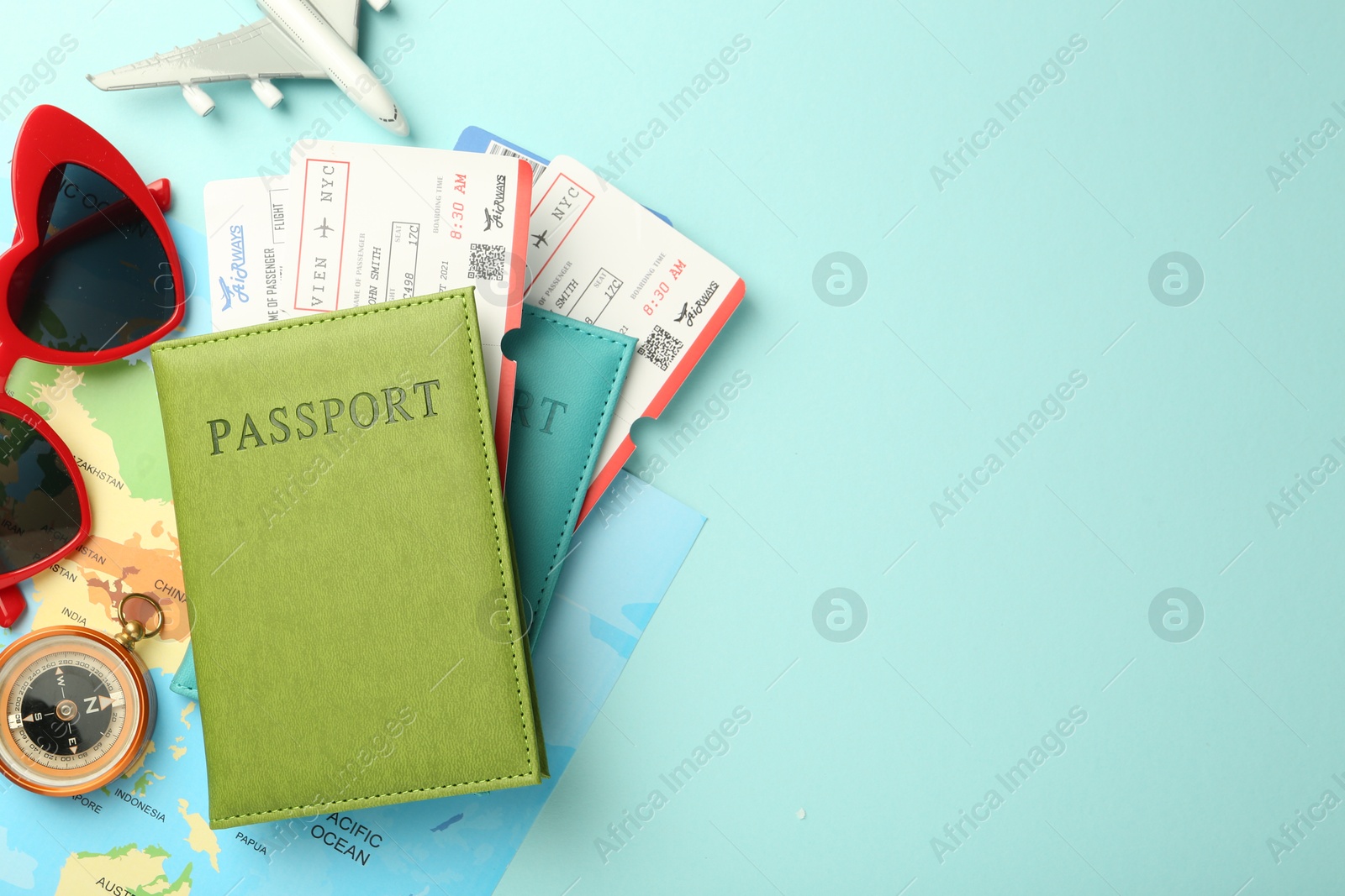 Photo of Passports with tickets, map, compass, plane model and sunglasses on light blue background, flat lay. Space for text