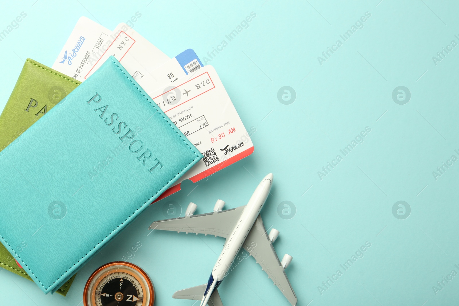 Photo of Passport with tickets, compass and plane model on light blue background, top view. Space for text