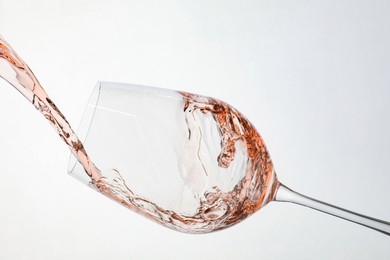 Photo of Pouring rose wine into glass on white background