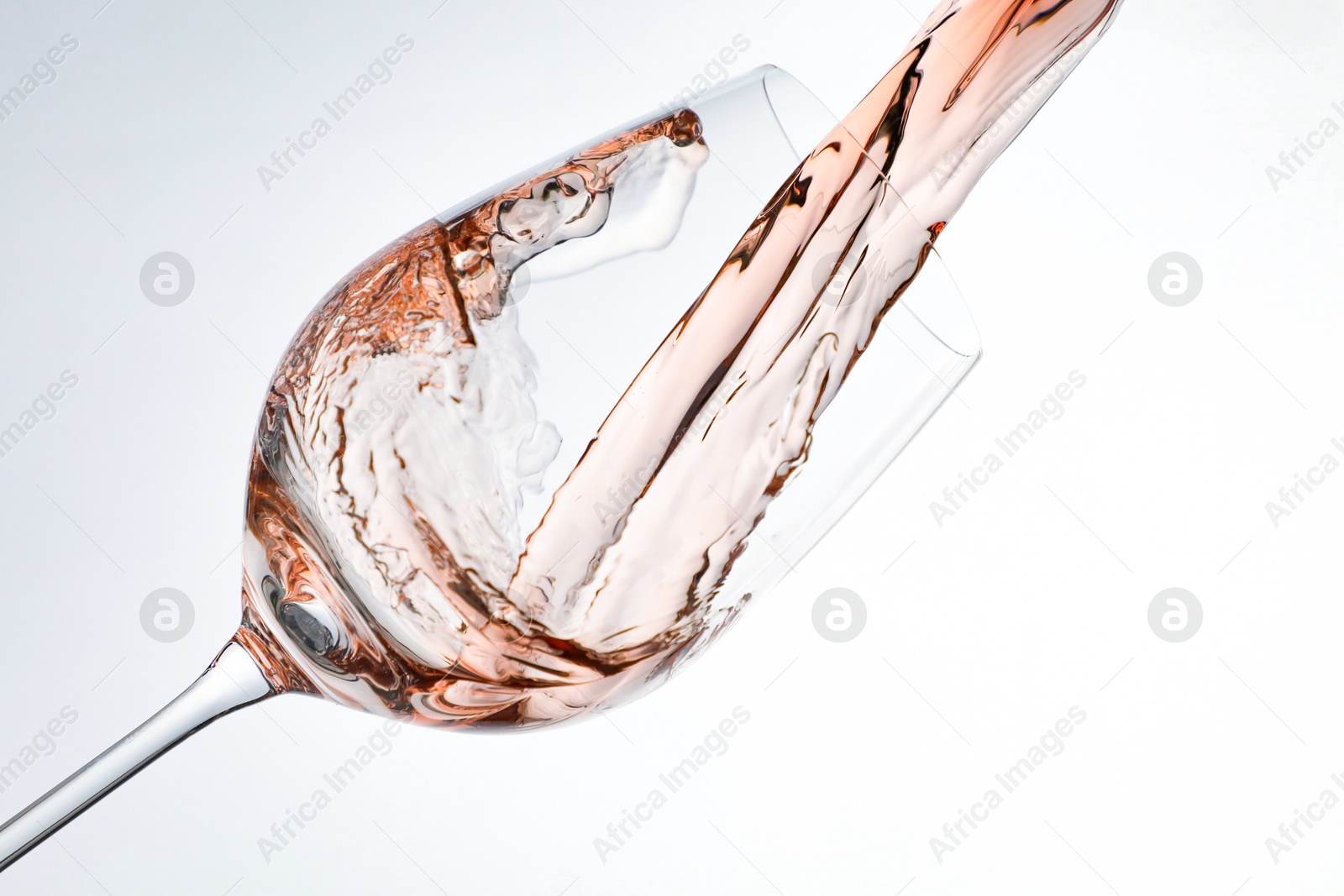 Photo of Pouring rose wine into glass on white background