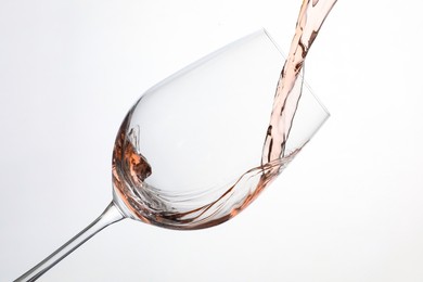 Photo of Pouring rose wine into glass on white background