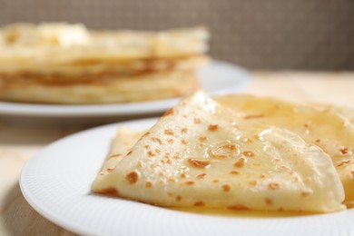 Photo of Tasty crepes with honey on wooden table, closeup