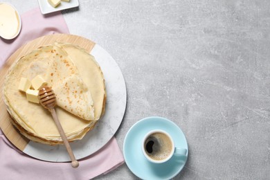 Photo of Tasty crepes with butter and honey served on grey textured table, flat lay. Space for text