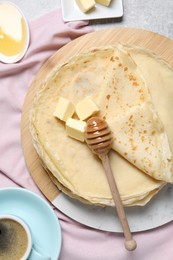 Photo of Tasty crepes with butter and honey served on grey textured table, flat lay