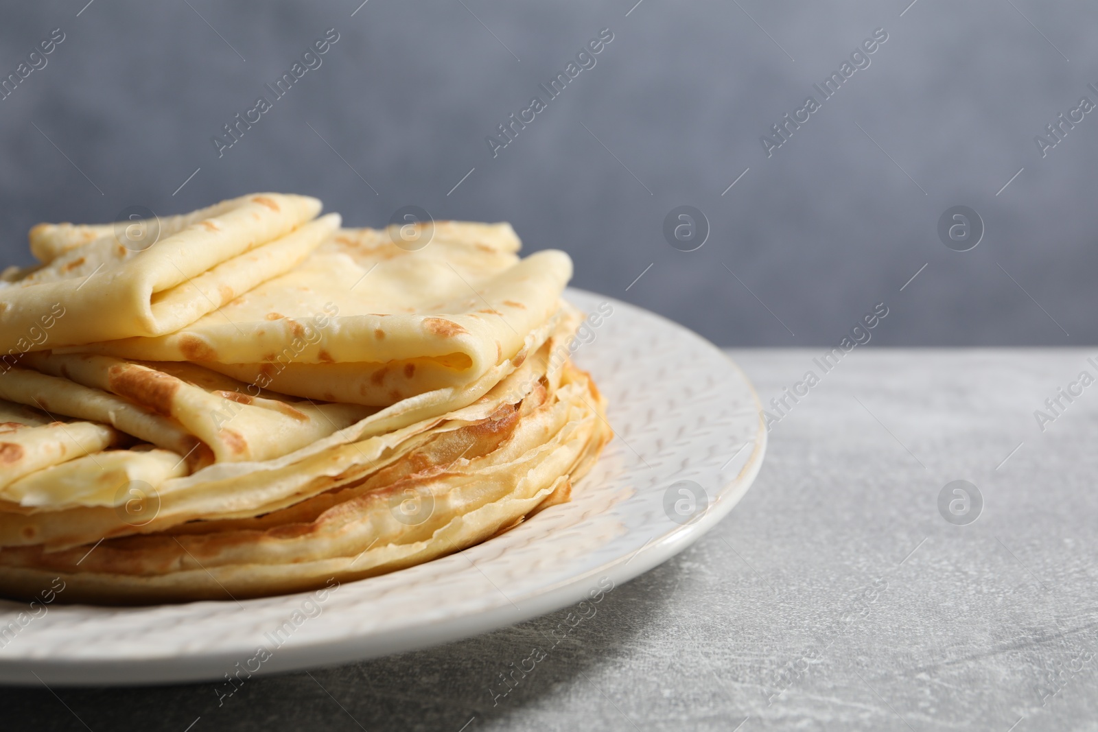 Photo of Tasty crepes on grey textured table, closeup. Space for text