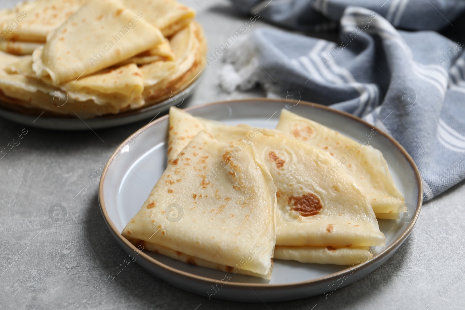 Photo of Tasty crepes on grey textured table, closeup