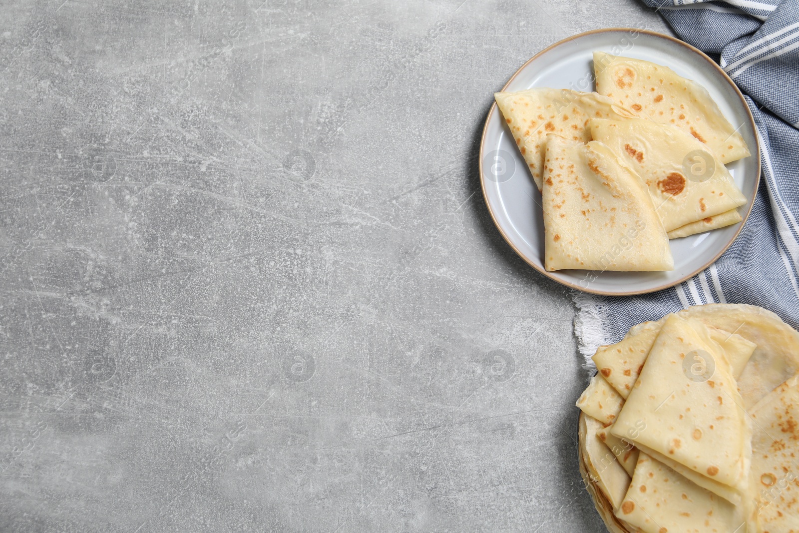 Photo of Tasty crepes on grey textured table, flat lay. Space for text