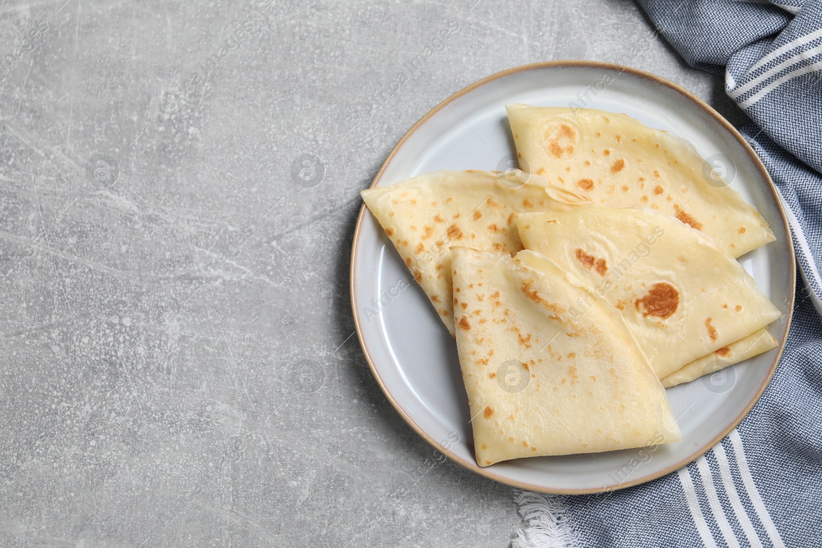 Photo of Tasty crepes on grey textured table, top view. Space for text