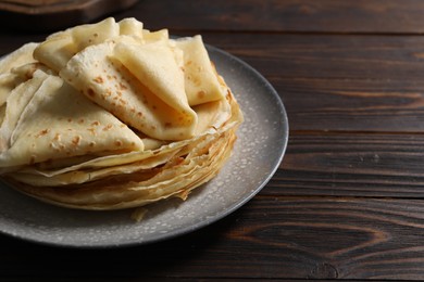 Photo of Tasty crepes on wooden table, closeup. Space for text