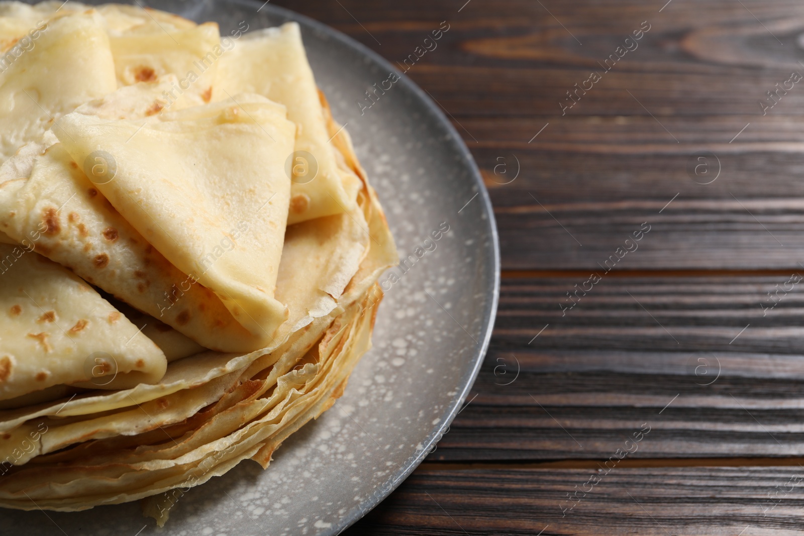 Photo of Tasty crepes on wooden table, closeup. Space for text