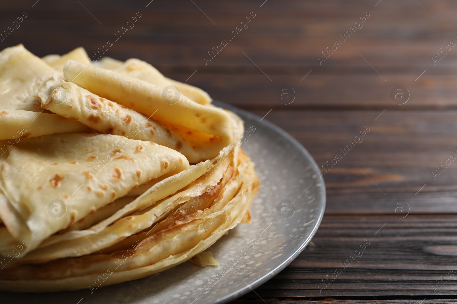 Photo of Tasty crepes on wooden table, closeup. Space for text