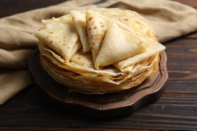 Photo of Tasty thin crepes on wooden table, closeup