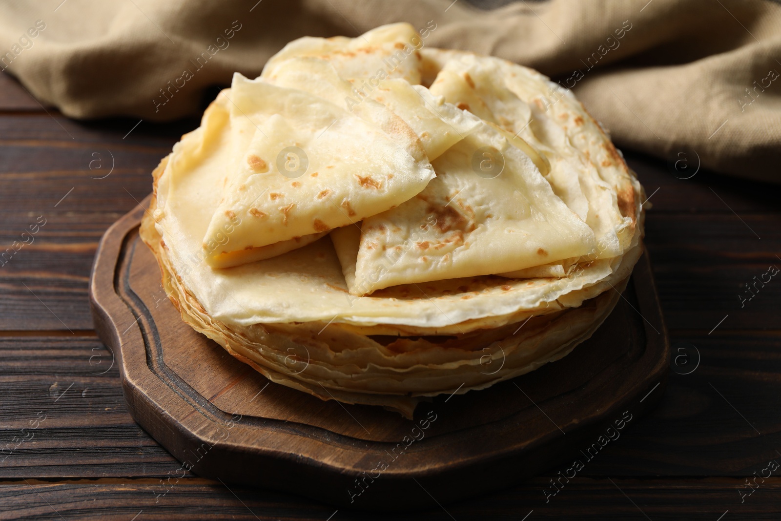 Photo of Tasty thin crepes on wooden table, closeup