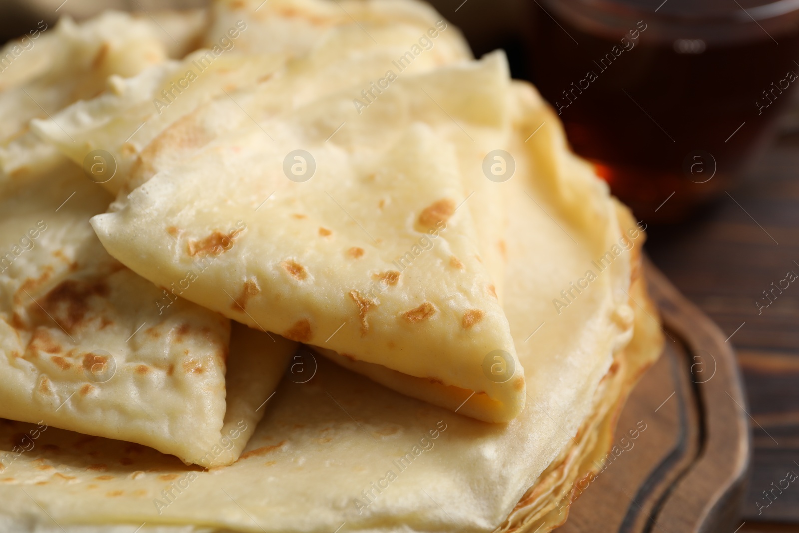 Photo of Tasty thin crepes on wooden table, closeup