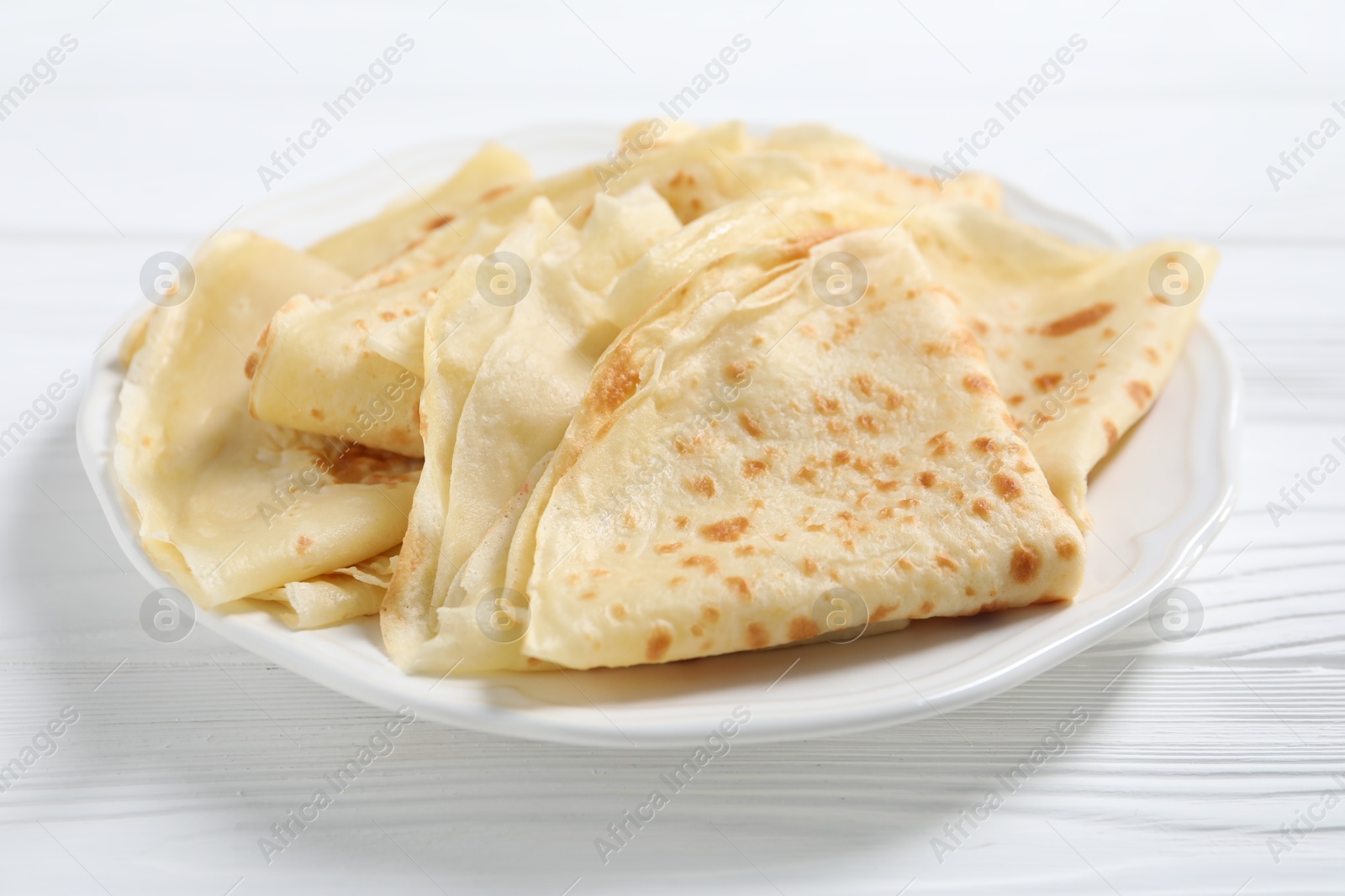 Photo of Tasty crepes on white wooden table, closeup