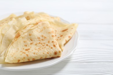 Tasty crepes on white wooden table, closeup. Space for text